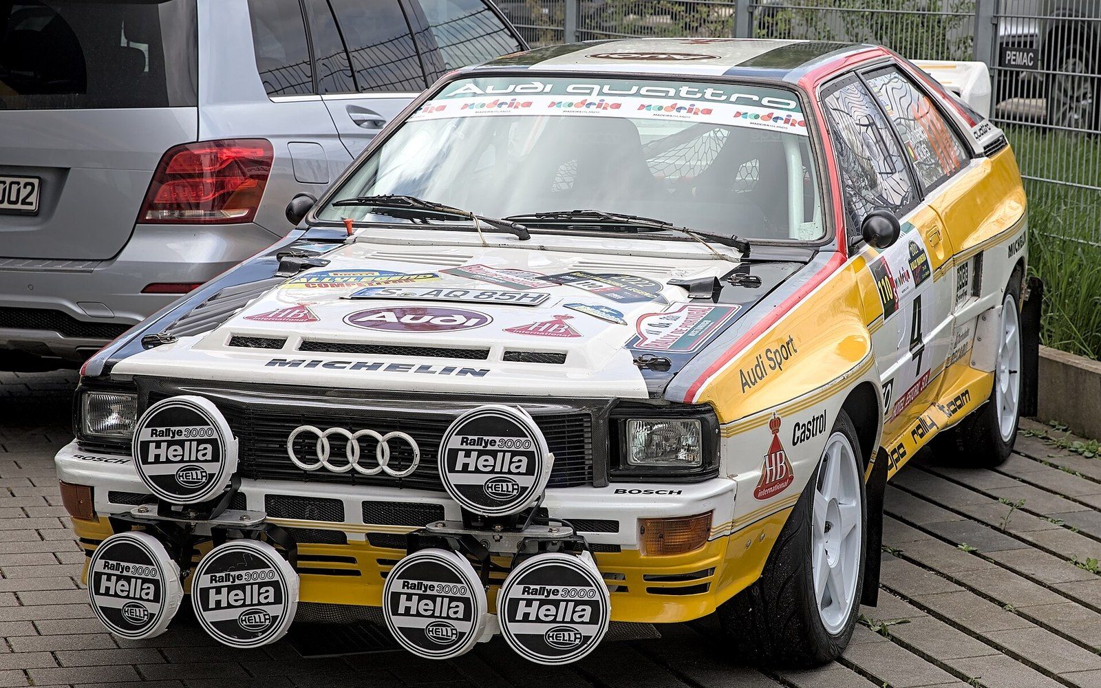 The Audi Quattro rally car in period competition livery, boxed wheel arches, on a gravel special stage